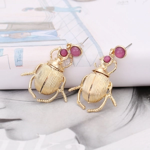 Vintage gold beetle earrings featuring pink resin stones and striped metallic texture