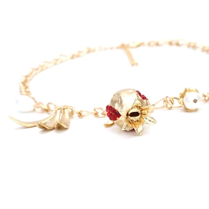 Macro detail of baroque pomegranate pendant with red beads and white pearl on gold chain