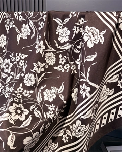 Close-up of silk satin scarf featuring white floral patterns and striped borders