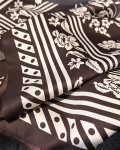Detail of silk-like scarf featuring elegant floral patterns and classic polka dot prints