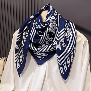 Close-up of navy blue silk-like square scarf with white floral print and border details
