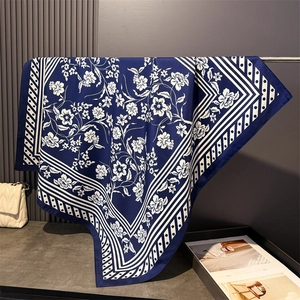 Detailed view of navy silk scarf with white floral prints and polka dot geometric borders