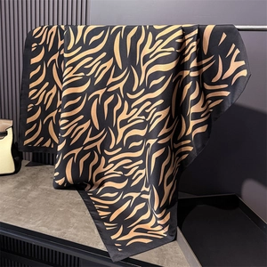 Détail du drapé d'un foulard en soie à motif tigre noir et doré sur support en métal