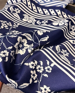 Detailed macro view of the navy blue floral silk scarf texture and smooth satin finish