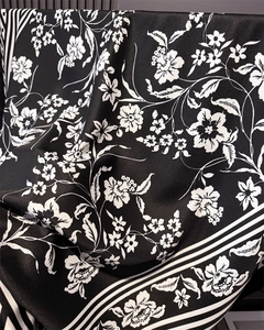 Detail of silk-like scarf featuring white floral prints and black striped border textures