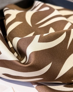 Détail macro du motif flamme marron et crème sur foulard en satin de soie drapé