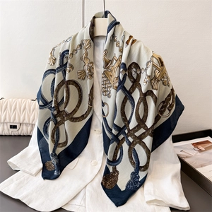 Retro silk scarf with nautical rope print and golden tassels over a white blazer