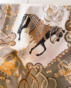 Close-up of silk scarf showing equestrian patterns with horses and golden chains