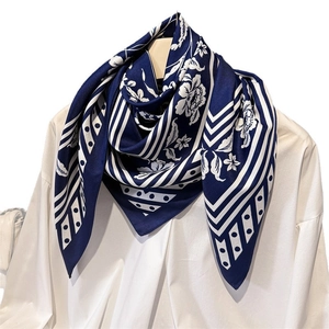 Navy and white printed silk scarf tied on a white shirt collar for office wear