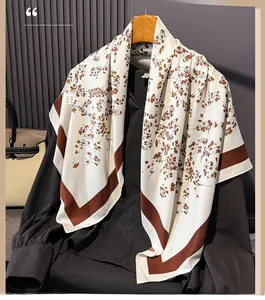 Detail of silk-like floral scarf with brown branch pattern on beige fabric and wide borders