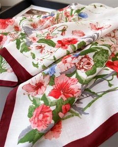 Close-up of floral print silk scarf with burgundy herringbone border on a black tray