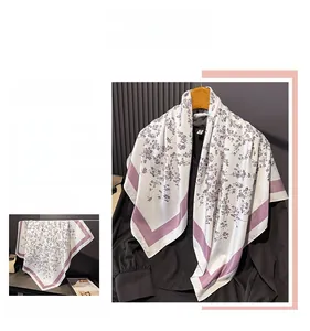 Detailed close-up of white silk scarf with purple floral print and elegant wide borders
