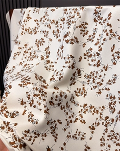 Detail of white satin scarf with brown floral patterns and soft silky textures