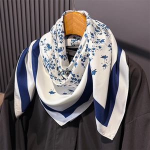 Romantic floral silk scarf in blue and white print draped on a wooden hanger