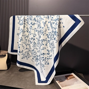 Detailed close-up of blue floral print on white faux silk scarf with navy borders