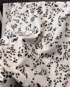 Close-up of black and white floral faux silk scarf fabric with smooth glossy texture