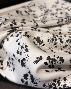 Detail of silk-like twill fabric featuring romantic black floral print on white background