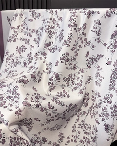 Detailed view of pearl white faux silk scarf with purple floral print and glossy texture