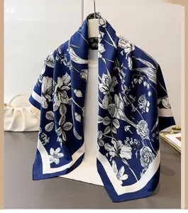Detail of dark blue silk scarf showing white floral patterns and premium satin texture