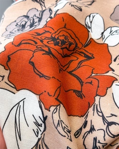 Close-up of twill fabric texture with romantic orange rose floral print on beige scarf