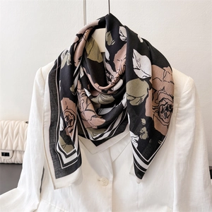Detail of vintage floral rose pattern on a black silk square scarf draped on a white blazer