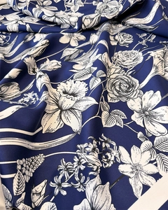Detailed view of floral patterns on navy silk-like scarf with elegant draped fabric texture