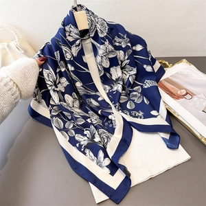 Detailed view of navy blue floral silk-like scarf draped elegantly on a hanger