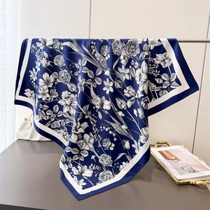 Detail of navy blue square silk scarf with white floral print draped on a metal rack
