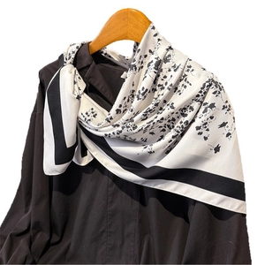 Elegant floral faux silk square scarf with bold black borders draped on a wooden hanger