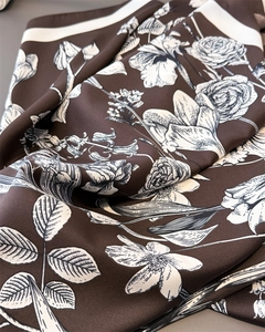 Macro shot of silk texture scarf with elegant white floral patterns on chocolate brown fabric