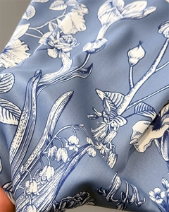 Detail of blue silk scarf showing white floral botanical print and smooth satin texture