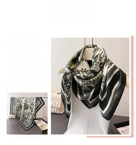 Detail of silk-feel square scarf featuring olive green leaf pattern and geometric borders