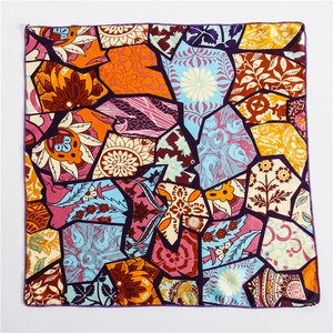 Detail of printed square scarf showing geometric floral patterns and purple hem stitching