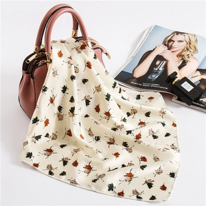 Elegant floral silk satin neckerchief draped over a pink handbag in a stylish setting