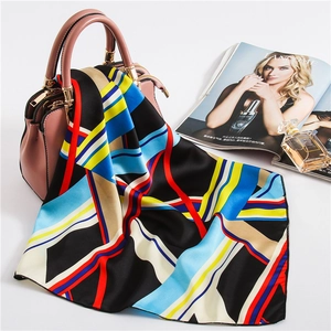 Colorful geometric silk scarf draped on a pink leather handbag with a fashion magazine