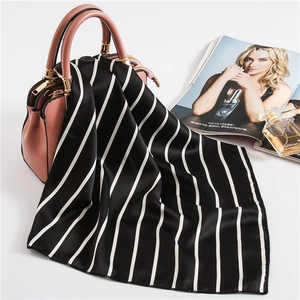 Detail view of a black and white striped silk scarf elegantly draped on a pink handbag