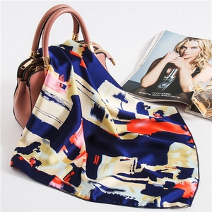 Silk satin square scarf with abstract patterns draped on a pink handbag for styling