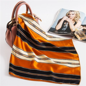 Detail of silk-like striped scarf tied on a bag with soft satin texture and rolled hem