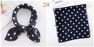 Detail of navy blue polka dot satin scarf shown folded and tied with floral prop