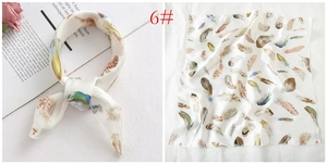 Detail of silk square scarf with colorful feather print and smooth texture in cream white