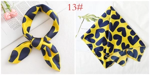 Detail of yellow silk satin square scarf with navy blue heart pattern and hemmed edges