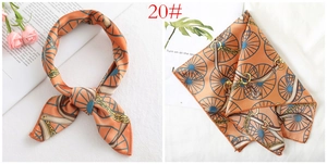 Detailed view of orange silk scarf featuring vintage chain patterns and chic belt motifs