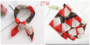 Detailed view of the silk satin scarf showing red and white geometric patterns and hem edges