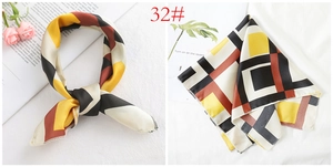 Detail of silk satin square scarf featuring geometric color blocks in yellow and burgundy