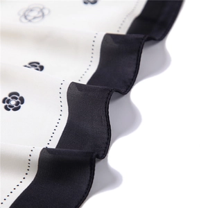Detailed close-up of silk scarf showing monochrome camellia floral pattern and fine texture