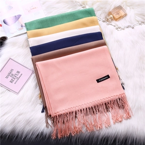 Soft cashmere-like solid scarves with fringe in multiple colors on plush background