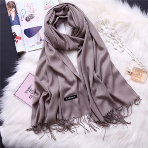 Close-up of soft purple cashmere scarf fringe with wash label on white faux fur