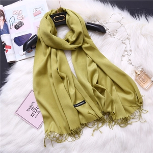 Detail shot of soft olive green cashmere scarf with fringe tassels on plush background