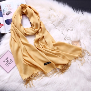 Detailed texture of ginger yellow cashmere scarf with fringes on a stylish background