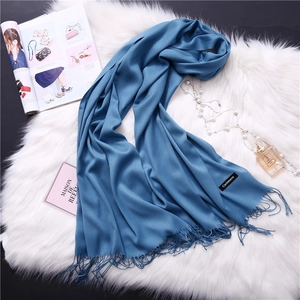 Close-up of blue cashmere scarf with fringe details on white faux fur background